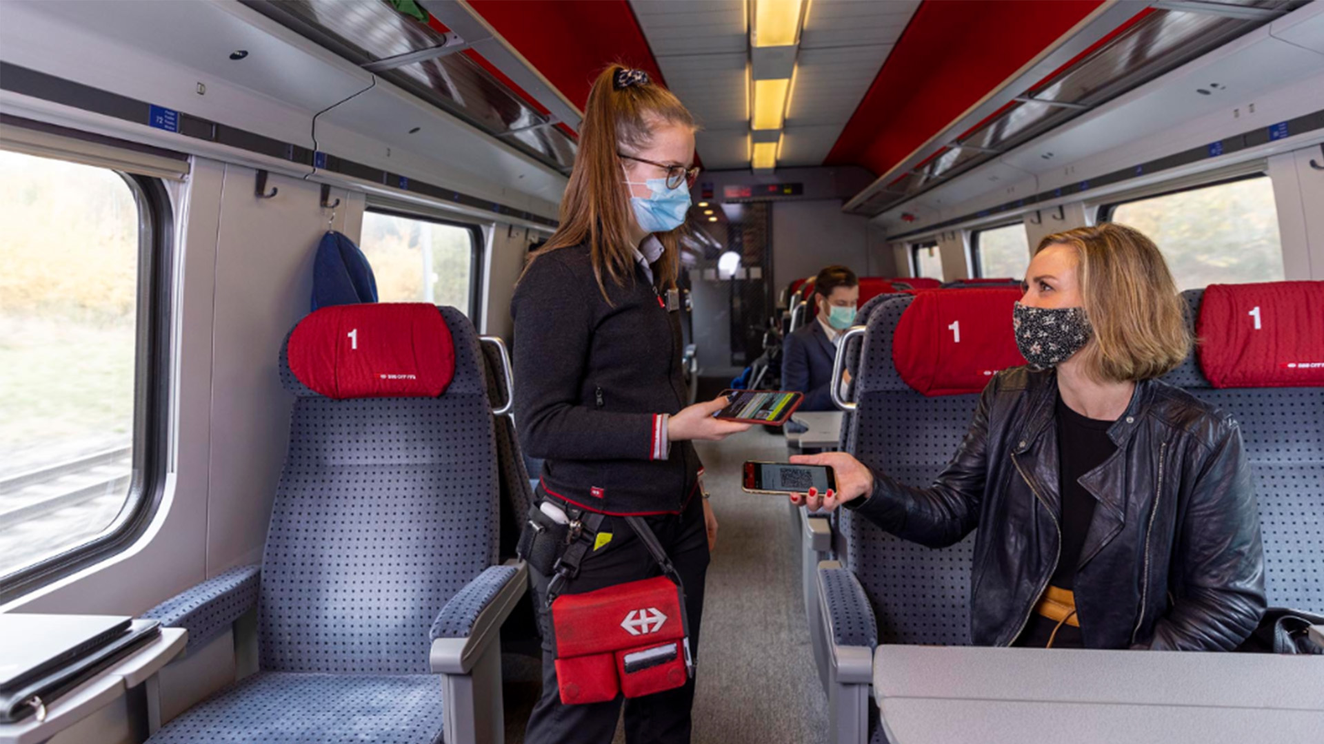 Des voyageurs et une contrôleuse portant un masque dans le train.